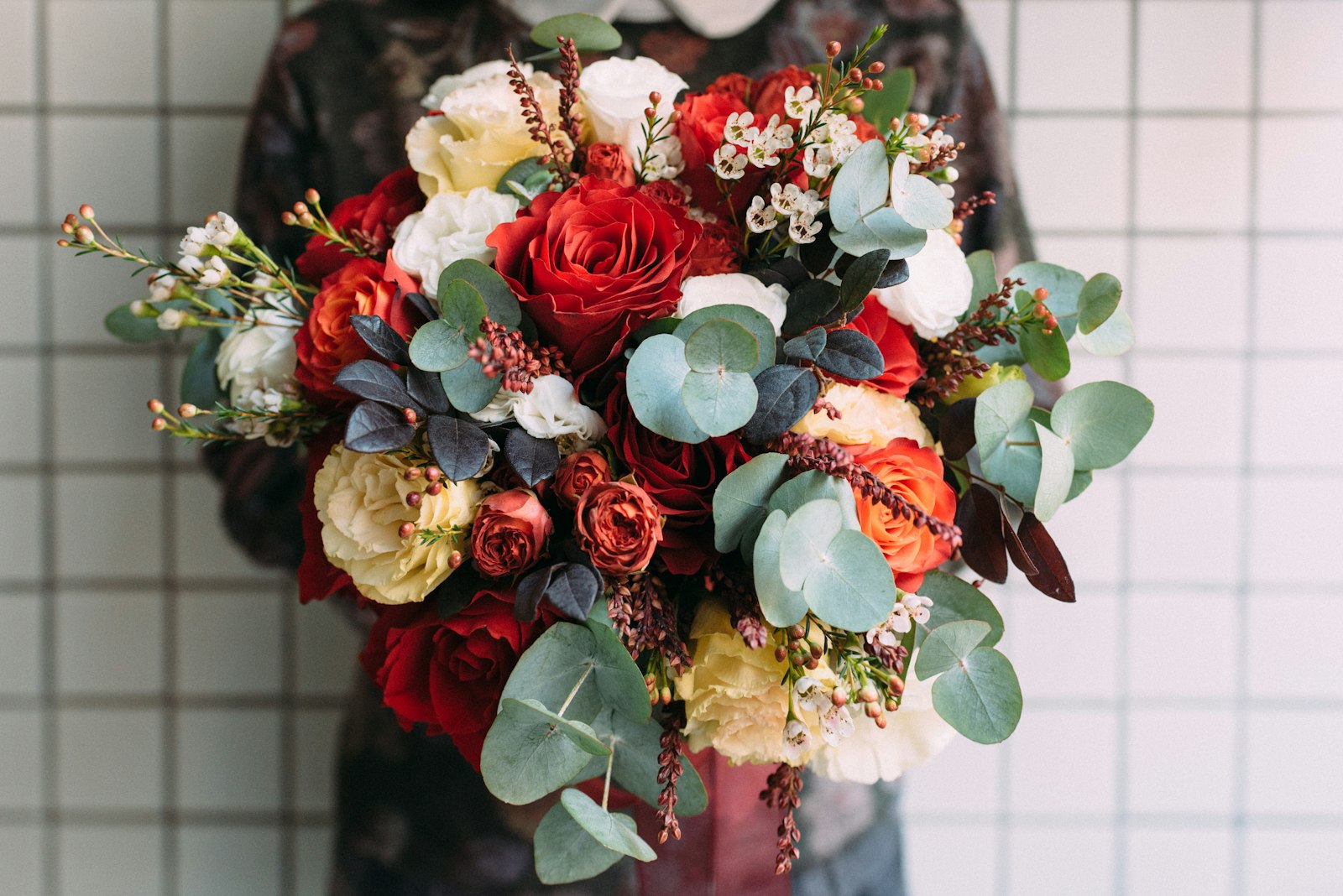 Ram de roses vermelles i flors clares amb eucaliptus.